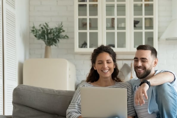 two people sitting on a couch and using a computer to adjust their WordPress featured image size